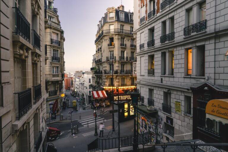 A street of Paris, France as the sun starts to set. The sky is a purple color.